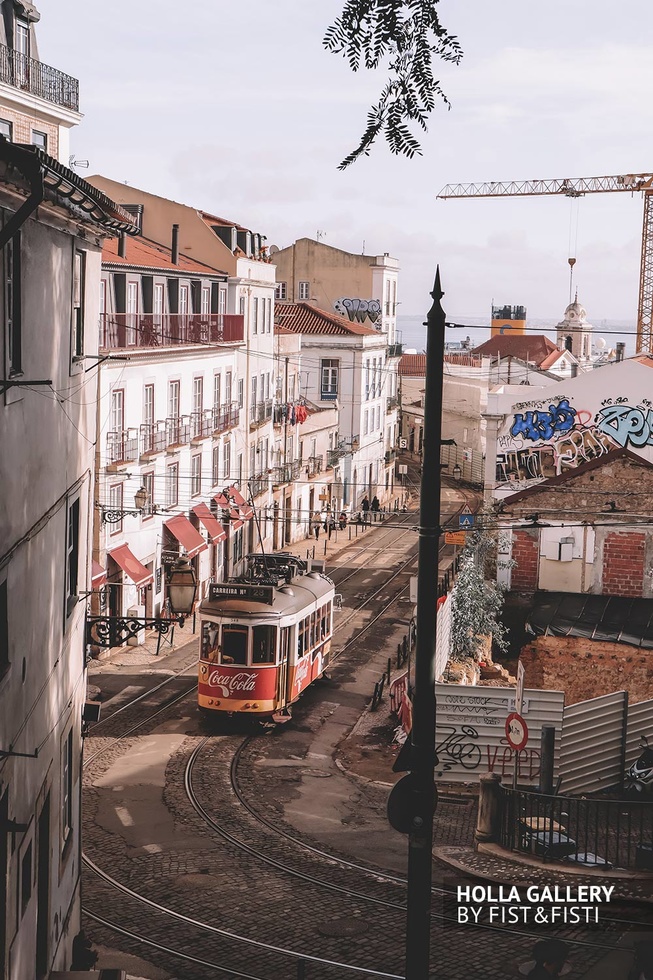 Трамвай на узкой улице в Лиссабоне на фоне граффити.