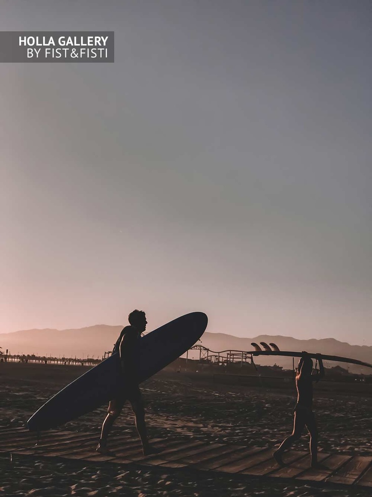 Серферы на пляже в Санта-Монике с досками в руках. Ясное небо и горы на фоне
