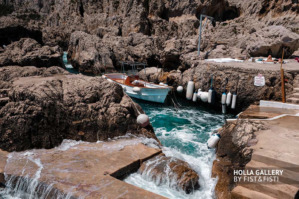 Пришвартованная лодка в узком проливе среди скал на Capri в Италии