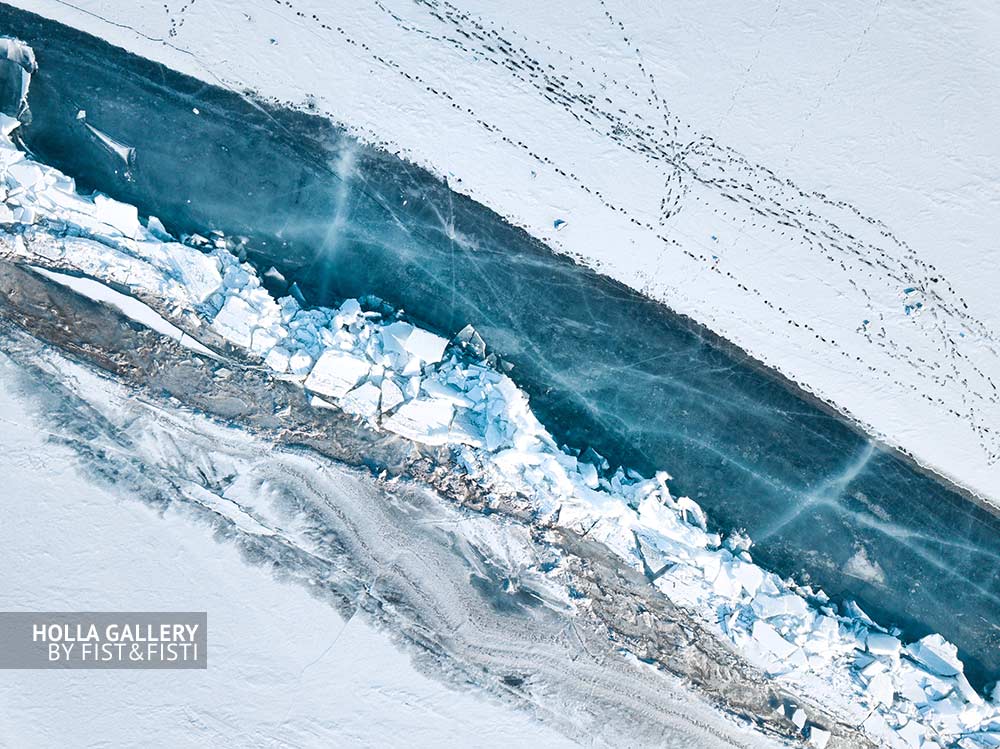 Вид сверху с коптера на побережье замёрзшего Байкала. Озеро во льду и следы человека. Фото для интерьера