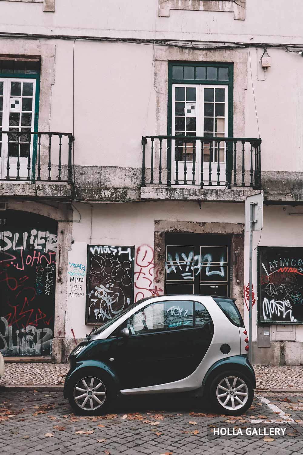 Черная машина у стены с граффити в Лиссабоне