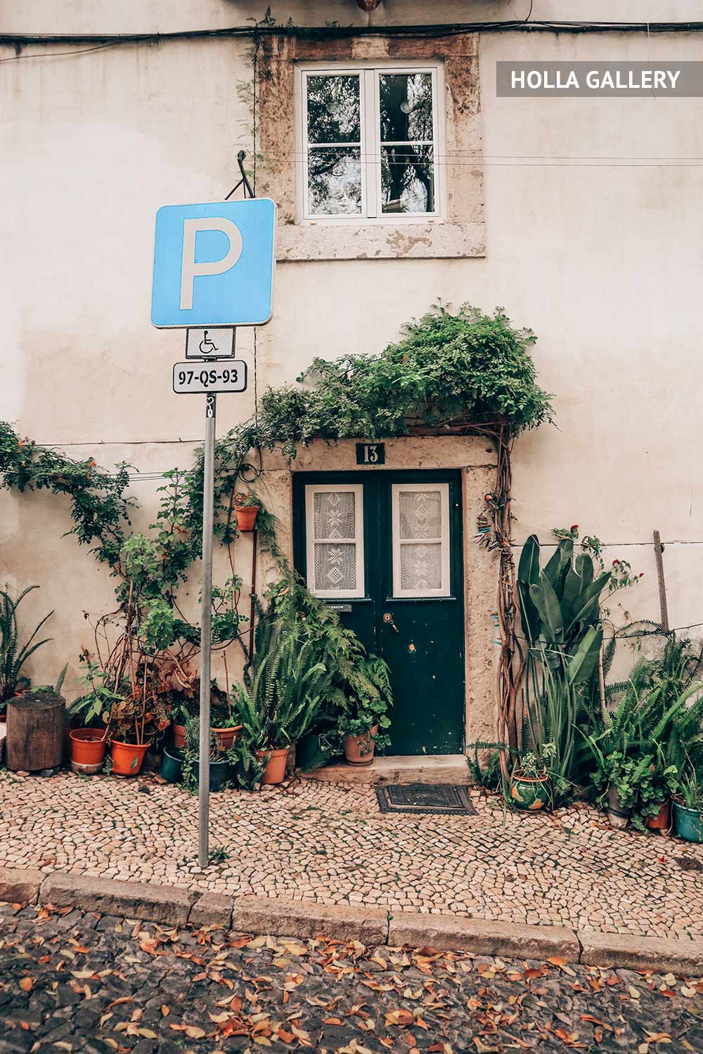 Заросшая дверь дома и знак парков в Лиссабоне
